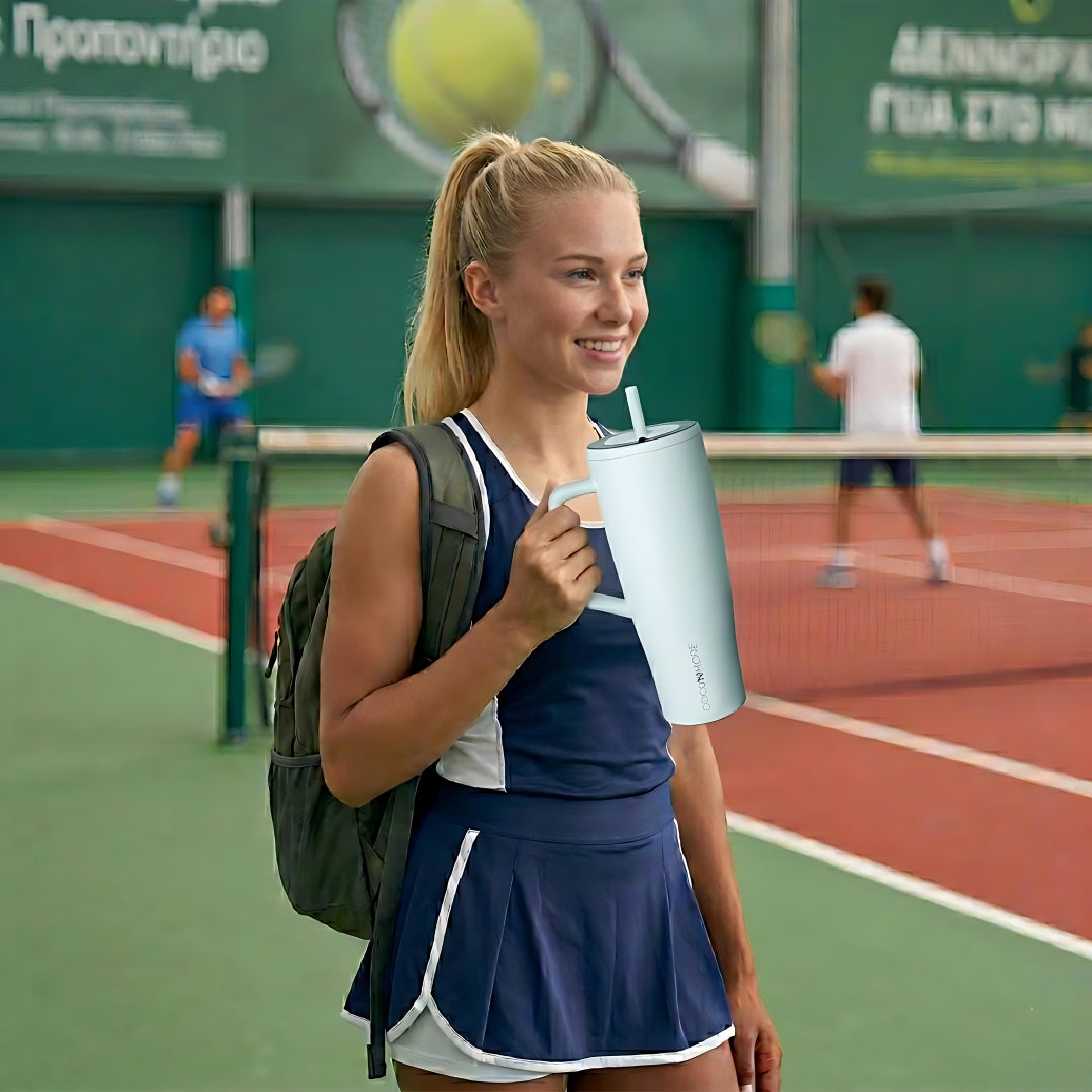 Woman in tennis court drinking from a light blue coolnmore Aqualis vogue tumbler θερμος 1200ml με καλαμακι 