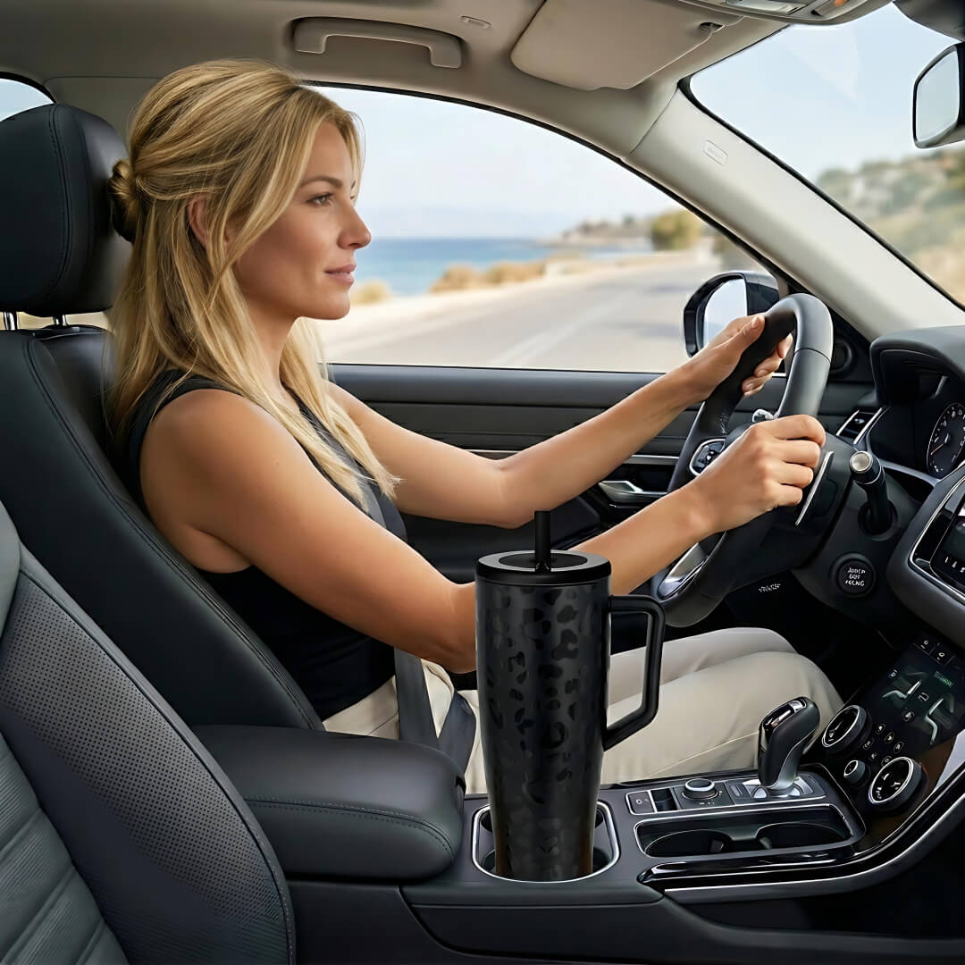 coolnmore vogue black leopard tumbler θερμος 1200ml με καλαμακι ανοξειδωτο.  Woman driving with her tumbler in cup holder