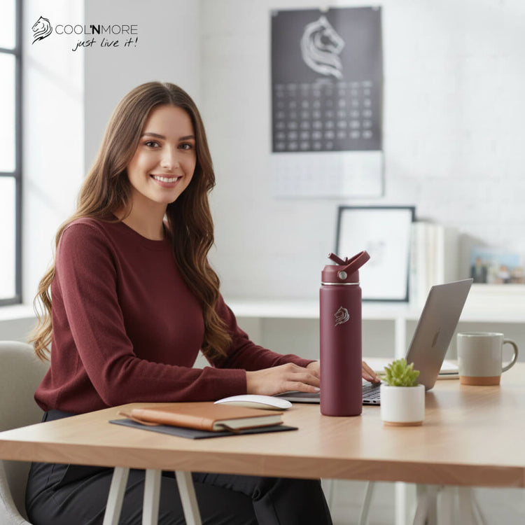 coolnmore θερμος νερου Vibe 750ml παγουρι θερμος. Woman sitting at a desk with a laptop and a purple water bottle, smiling.