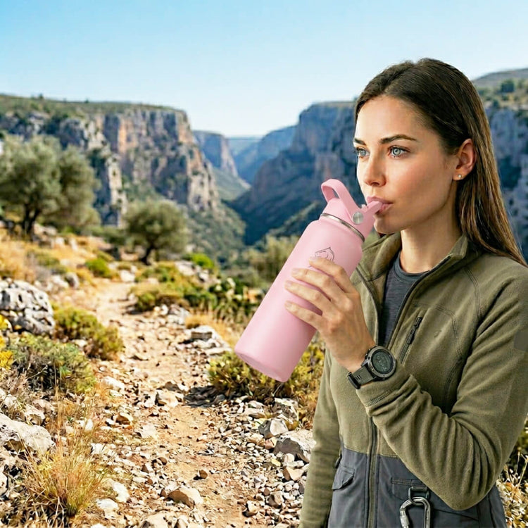 Coοlnmore Flamingo θερμος νερου 1 λιτρου. Woman drinking from a pink water bottle in a scenic outdoor setting with mountains.