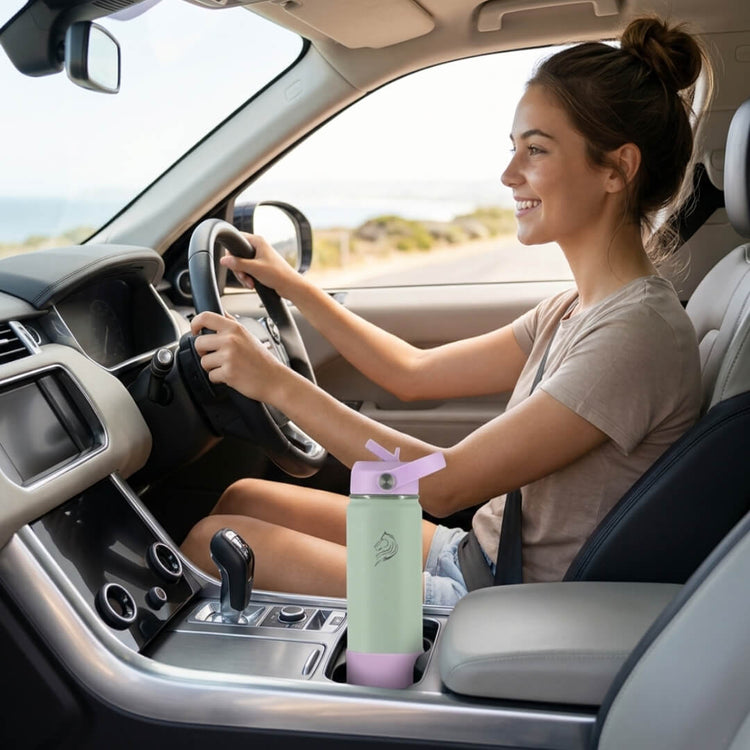 Woman driving a car with a green and pink water bottle on the passenger seat. Coolnmore Mino παιδικο παγουρι θερμος νερου 350ml. 