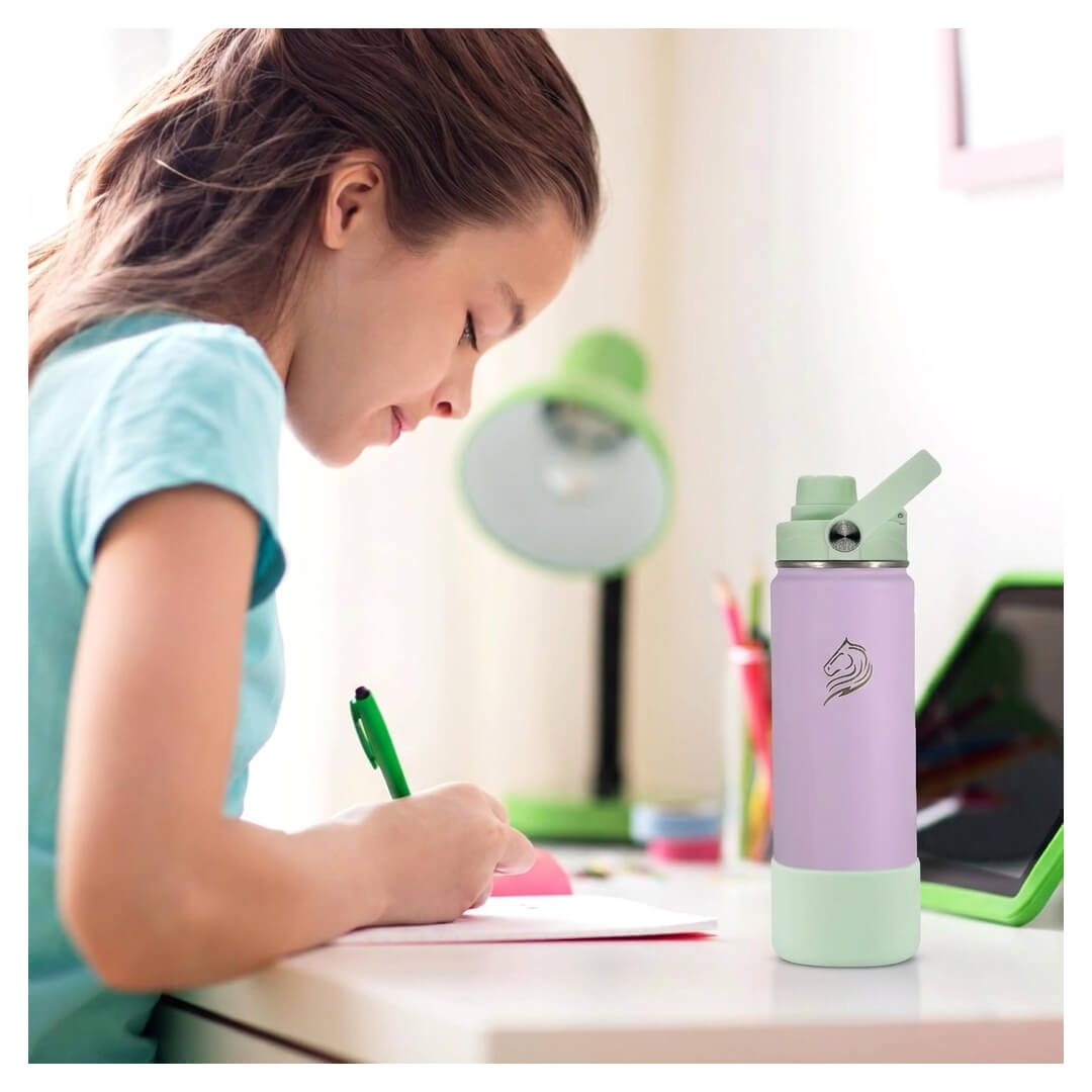 Το Coolnmore Nook παιδικο παγουρι θερμος 500ml. Child writing at a desk with a purple and green water bottle nearby