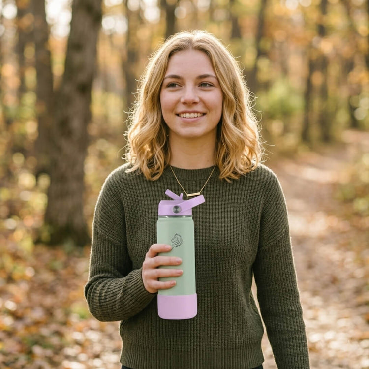 Το Coolnmore Nook μπουκαλι θερμος 500ml με καλαμακι. Woman holding a green and pink water bottle in a forest setting
