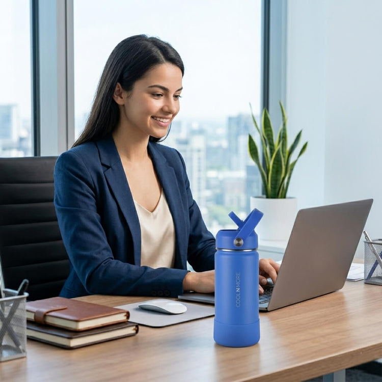 Coolnmore Royal Blue παιδικο παγουρι θερμος 350ml. Woman sitting at a desk with a laptop, smiling, and a blue water bottle on the desk.