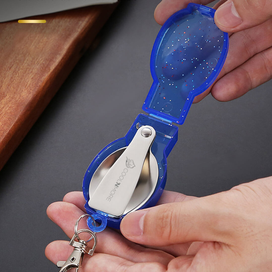 Blue pocket Spork with a keychain attachment held by a hand on a dark surface.